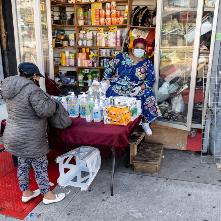 May 3, 2020: African woman selling disposable gloves, rubbing alcohol, and hand sanitizer at 939 Southern Boulevard, Bronx, New York. She asked me, “Papi, why are you taking pictures?” © Camilo José Vergara 