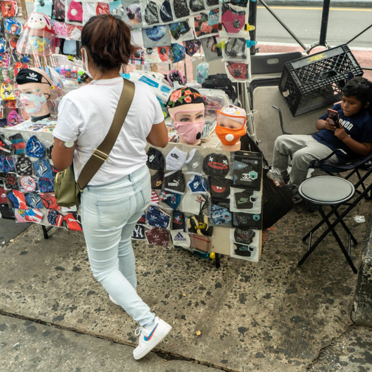 September 17, 2020: Selling masks while taking care of her child. East 149th Street at Melrose Avenue, Bronx, New York. © Camilo José Vergara 