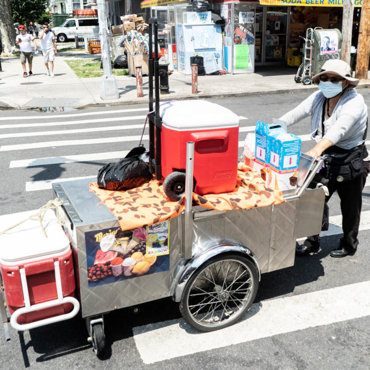 July 25, 2020: Maria, originally from Ecuador, on her way to her spot to sell Italian ices. 37th Avenue at 99th Street, Queens, New York. © Camilo José Vergara 